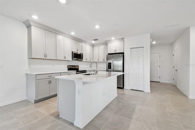 kitchen featuring light tile patterned floors, appliances with stainless steel finishes, sink, and an island with sink