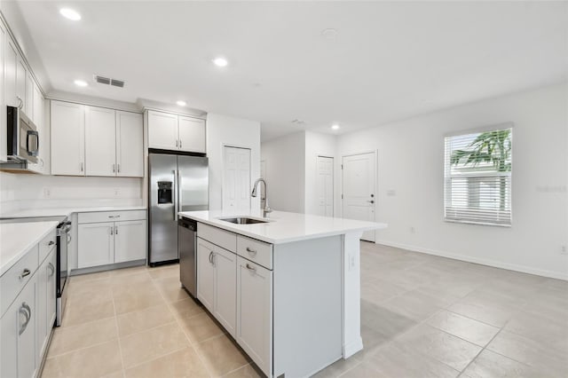 kitchen featuring light tile patterned flooring, stainless steel appliances, a kitchen island with sink, and sink