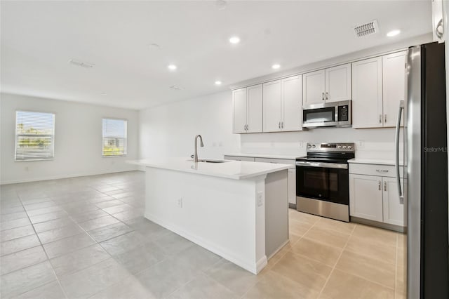 kitchen featuring sink, an island with sink, stainless steel appliances, white cabinets, and light tile patterned floors