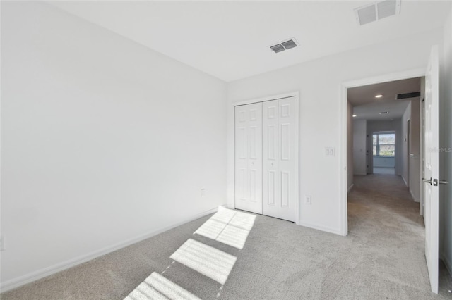 unfurnished bedroom featuring light carpet and a closet