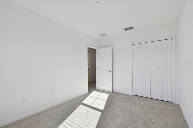 unfurnished bedroom featuring light colored carpet and a closet