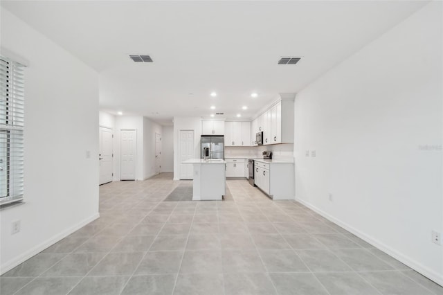 kitchen with white cabinetry, light tile patterned floors, a center island, and stainless steel appliances