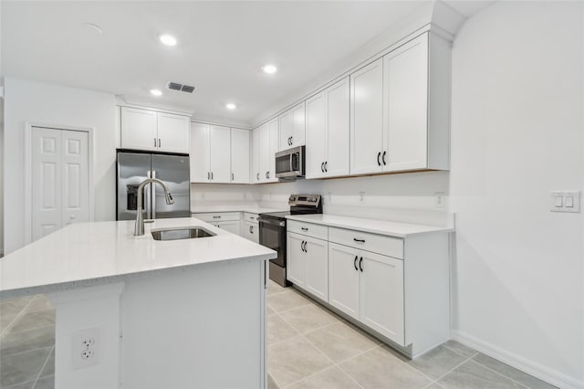 kitchen featuring appliances with stainless steel finishes, sink, white cabinetry, and a center island with sink