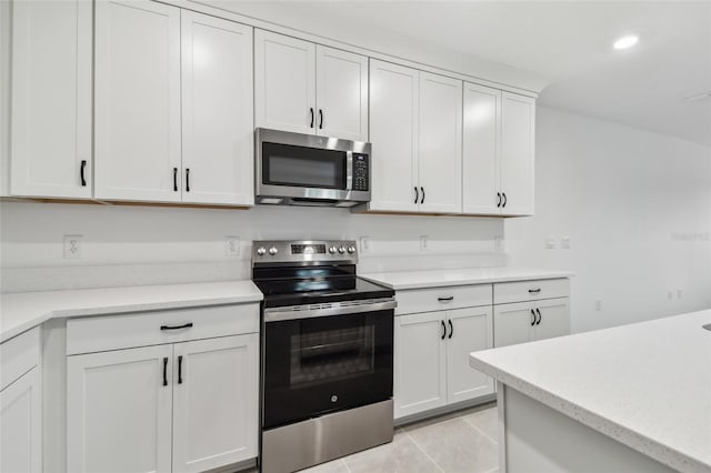 kitchen with white cabinets, appliances with stainless steel finishes, and light tile patterned flooring