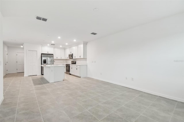 kitchen with light tile patterned floors, stainless steel appliances, a center island, white cabinets, and sink