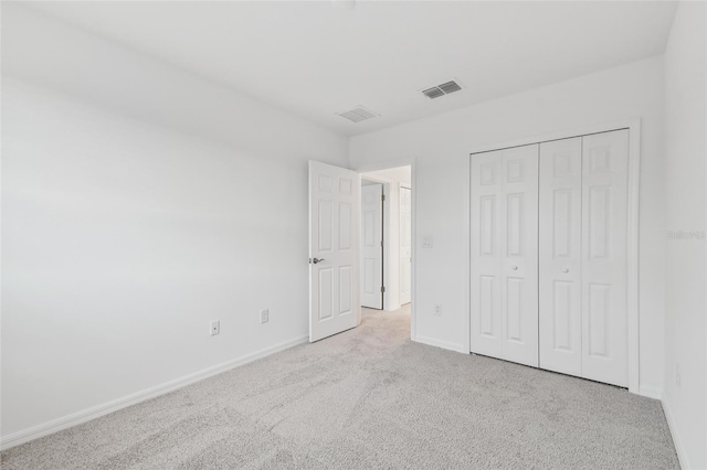 unfurnished bedroom with light carpet and a closet