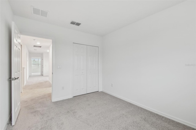 unfurnished bedroom with light carpet and a closet