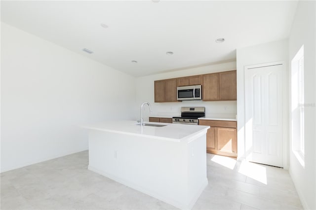 2203 Carson Loop, Lake Wales, FL 33859 - kitchen with stainless steel appliances, a kitchen island with sink, a sink, brown cabinetry, and light countertops