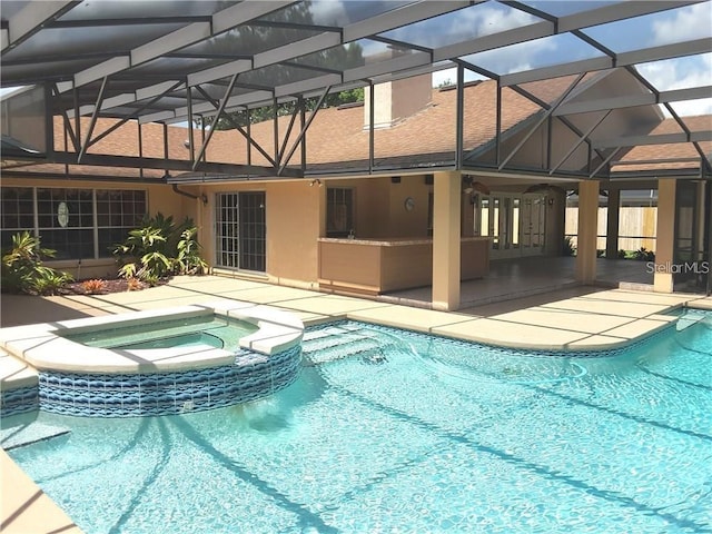 view of swimming pool featuring glass enclosure, a patio area, and an in ground hot tub