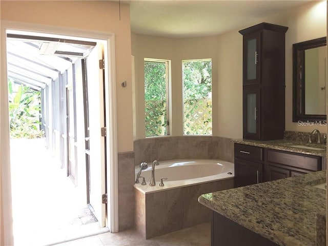 bathroom with tile patterned floors, vanity, and tiled tub