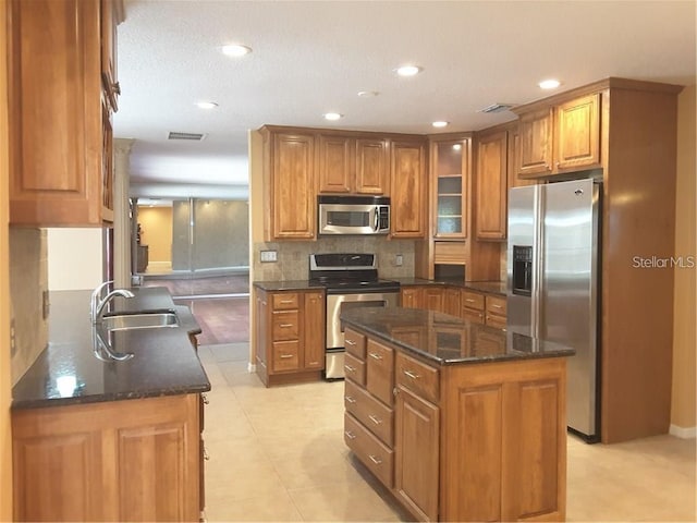 kitchen featuring dark stone counters, sink, a kitchen island, and stainless steel appliances