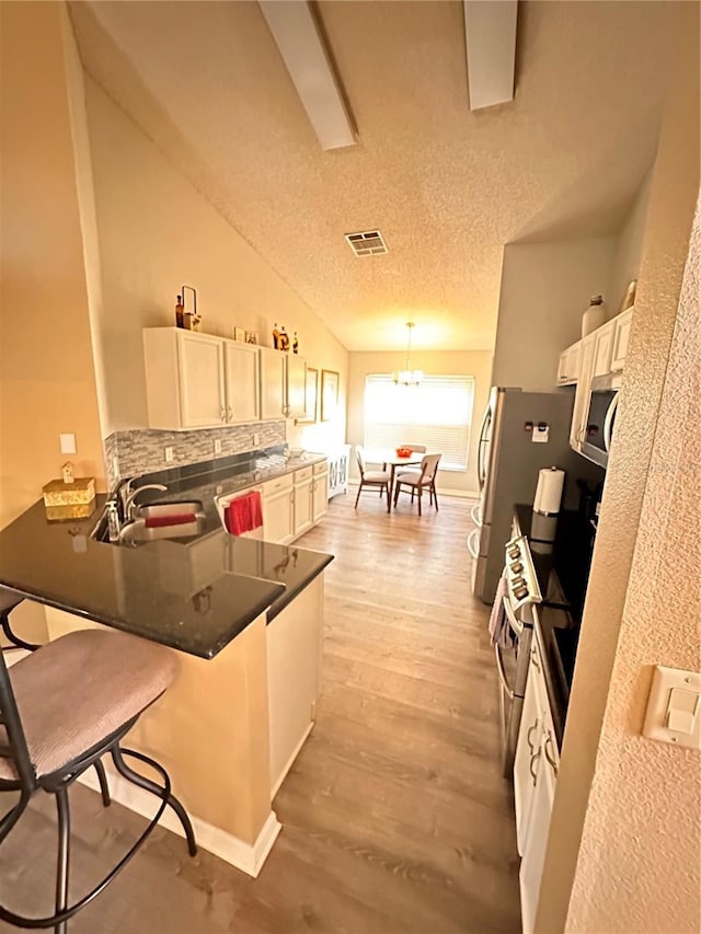 kitchen with kitchen peninsula, sink, light hardwood / wood-style flooring, white cabinets, and a breakfast bar area