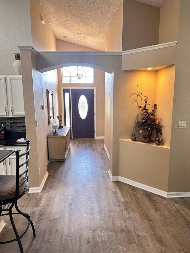 entrance foyer featuring hardwood / wood-style floors, a textured ceiling, and high vaulted ceiling