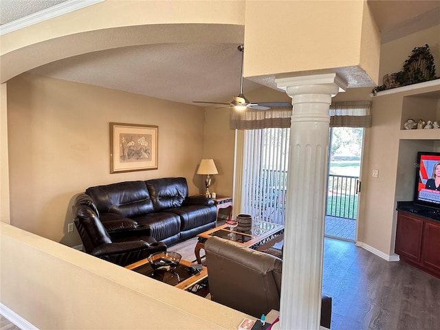 living room featuring dark hardwood / wood-style flooring, ornate columns, ornamental molding, a textured ceiling, and ceiling fan