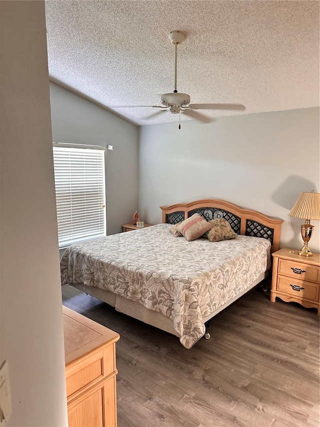 bedroom with ceiling fan, dark hardwood / wood-style floors, and a textured ceiling