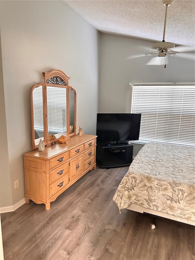 bedroom with ceiling fan, wood-type flooring, and a textured ceiling