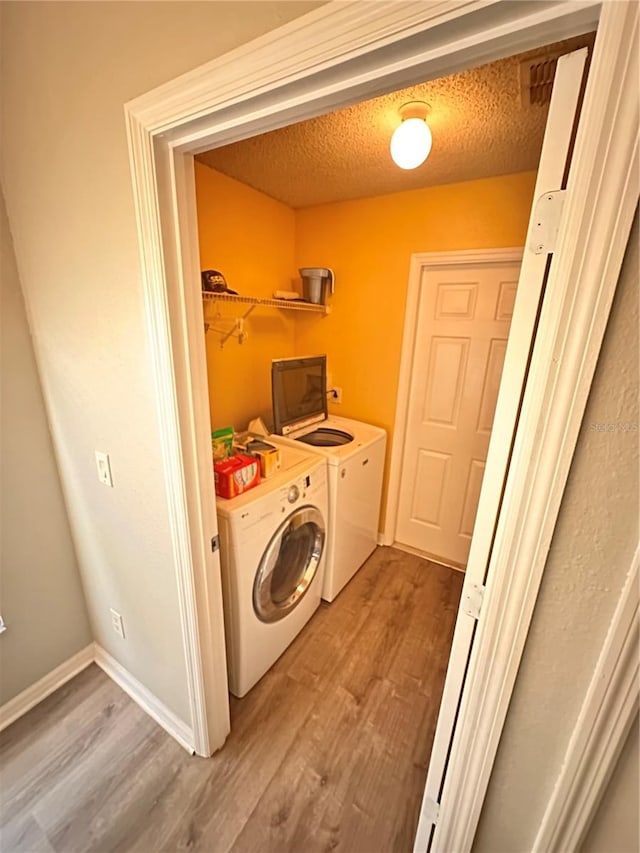 laundry room with washer and dryer, a textured ceiling, and hardwood / wood-style flooring