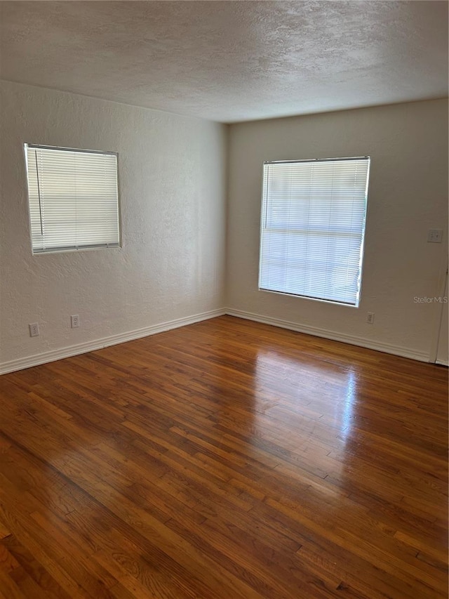 unfurnished room with a textured ceiling and dark hardwood / wood-style flooring