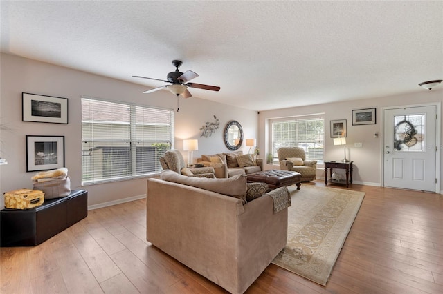 living room featuring a textured ceiling, light hardwood / wood-style floors, and ceiling fan