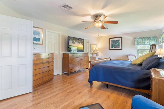 bedroom featuring ceiling fan, light hardwood / wood-style floors, and a textured ceiling