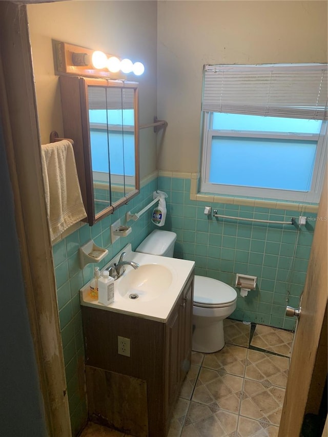 bathroom with tile patterned floors, vanity, tile walls, and toilet