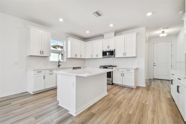 kitchen with a kitchen island, white cabinetry, sink, and appliances with stainless steel finishes