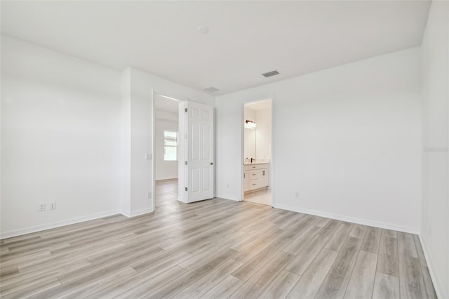 unfurnished bedroom featuring light hardwood / wood-style flooring and ensuite bath