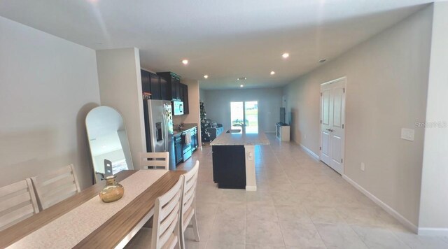 kitchen featuring light stone counters, blue cabinets, light tile patterned floors, stainless steel fridge with ice dispenser, and a center island