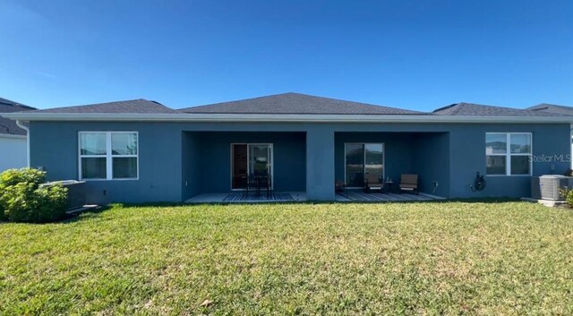 rear view of property featuring a patio, cooling unit, and a lawn