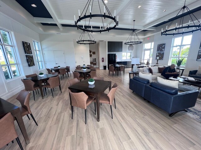 dining space with beamed ceiling, light hardwood / wood-style floors, and a chandelier