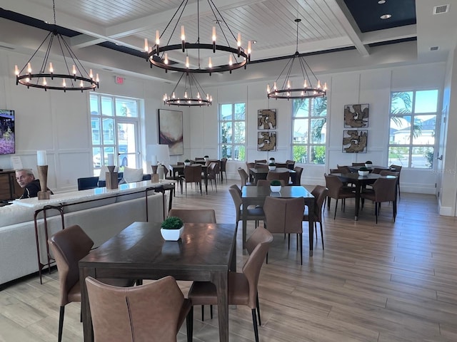 dining space with a chandelier, light hardwood / wood-style flooring, and beamed ceiling