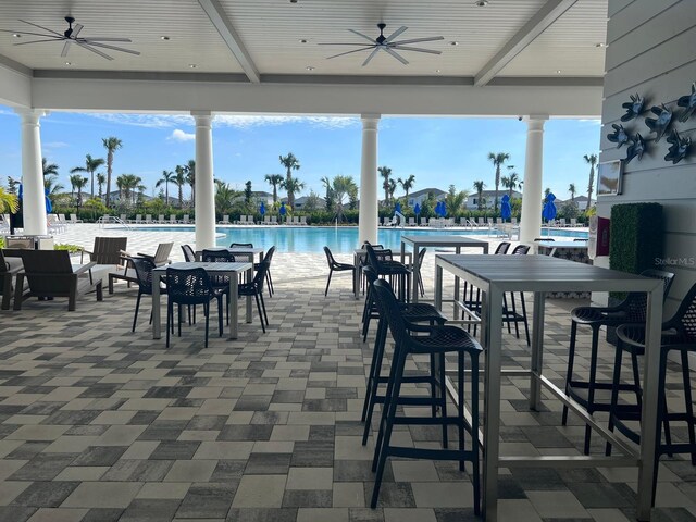 view of patio / terrace with ceiling fan, a community pool, and a water view