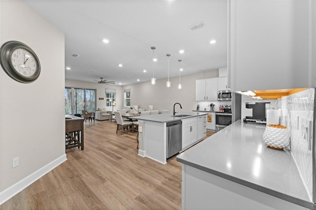 kitchen featuring white cabinets, stainless steel appliances, ceiling fan, and a center island with sink