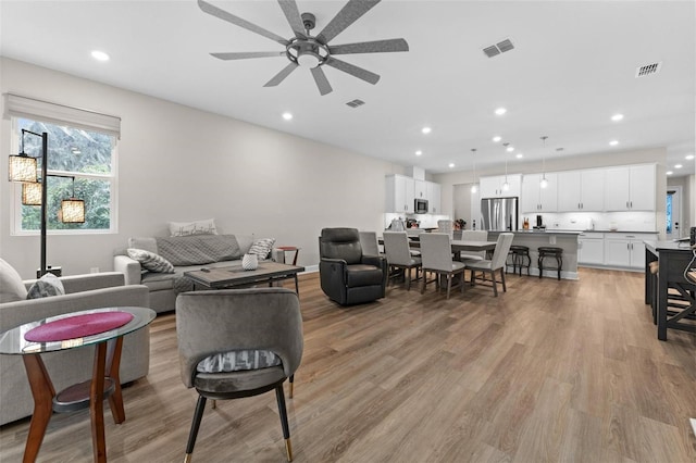 living room with ceiling fan and light hardwood / wood-style flooring