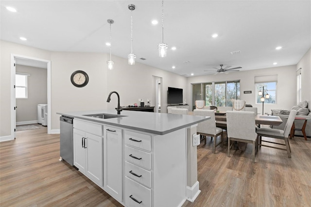 kitchen with stainless steel dishwasher, ceiling fan, sink, white cabinetry, and an island with sink