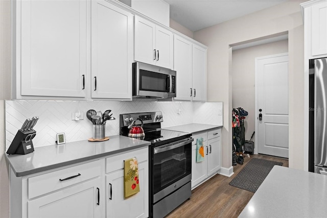 kitchen with white cabinets, appliances with stainless steel finishes, decorative backsplash, and dark hardwood / wood-style floors