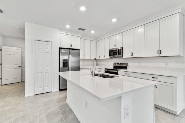 kitchen featuring sink, light tile patterned floors, white cabinetry, stainless steel appliances, and an island with sink