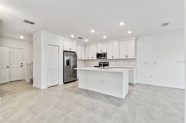 kitchen with a kitchen island with sink, sink, white cabinets, and appliances with stainless steel finishes