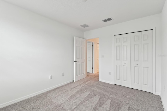 unfurnished bedroom featuring light carpet and a closet