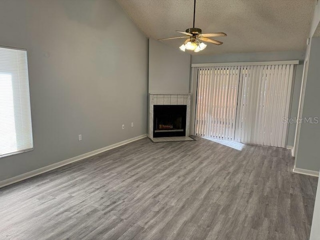 unfurnished living room with a tile fireplace, hardwood / wood-style floors, a textured ceiling, and ceiling fan