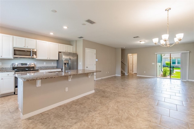 kitchen featuring light stone countertops, a kitchen bar, a kitchen island with sink, and appliances with stainless steel finishes