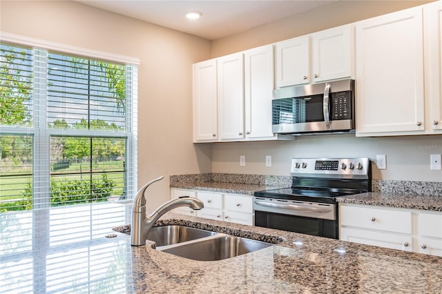 kitchen featuring sink, white cabinets, light stone counters, and appliances with stainless steel finishes