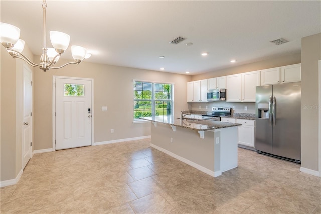 kitchen featuring stainless steel appliances, white cabinetry, decorative light fixtures, and a kitchen island with sink