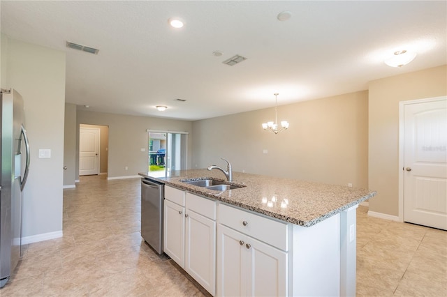 kitchen featuring a center island with sink, stainless steel appliances, pendant lighting, sink, and white cabinetry