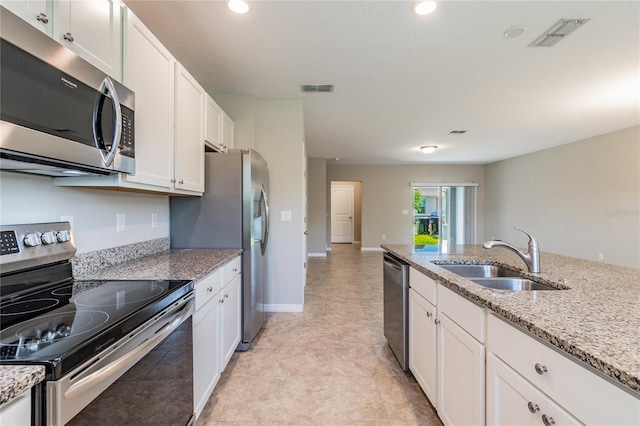 kitchen with stainless steel appliances, white cabinetry, sink, and light stone counters