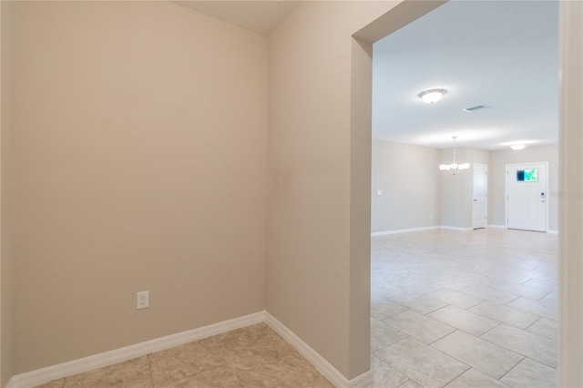 empty room with a chandelier and light tile patterned floors