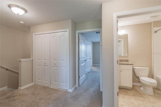 corridor featuring a textured ceiling and light colored carpet