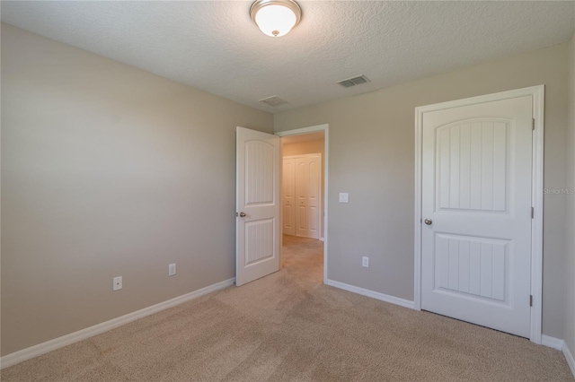 unfurnished bedroom with a textured ceiling and light carpet