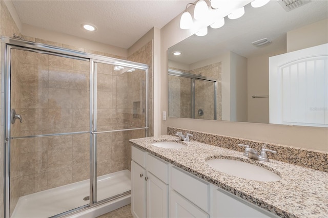 bathroom with a textured ceiling, a shower with shower door, and vanity