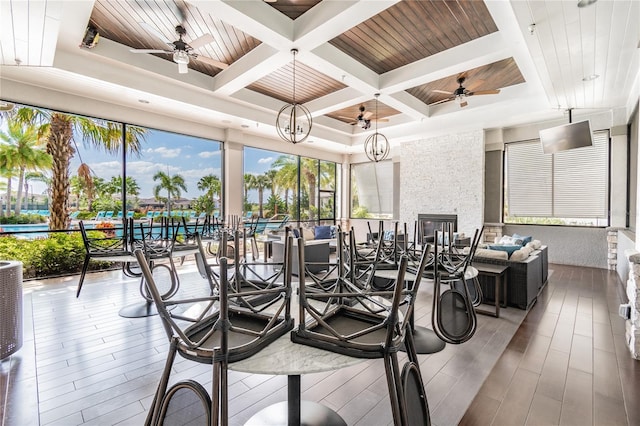 sunroom / solarium featuring ceiling fan with notable chandelier and wood ceiling